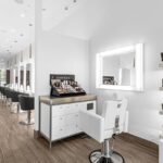 Modern hair and skincare salon interior with styling stations, mirrors, black chairs, product displays, and bright white lighting. - Salon Dulay, FL